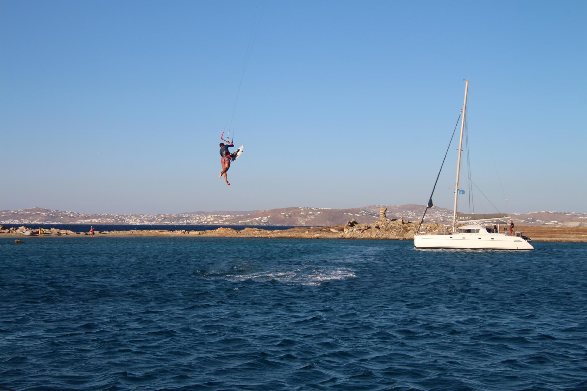 http://A%20kitesurfer%20performing%20a%20high%20jump%20near%20a%20catamaran%20anchored%20off%20the%20coast%20of%20a%20Greek%20island%20during%20a%20kite%20cruise%20in%20the%20Cyclades.